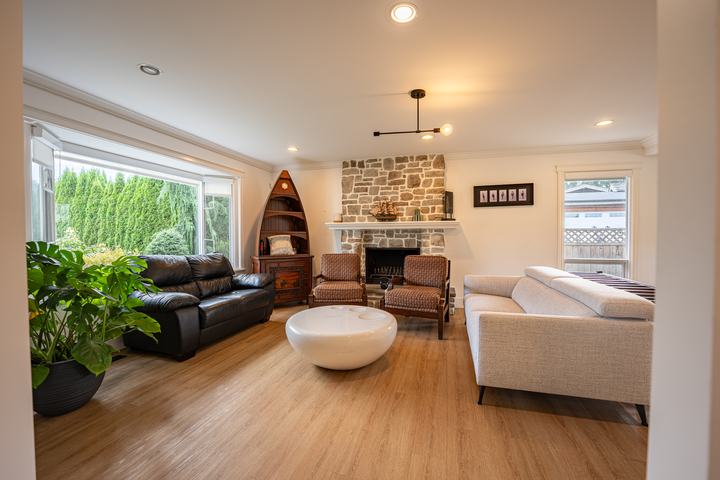 Living room with a stone fireplace, bay window and leather sofas