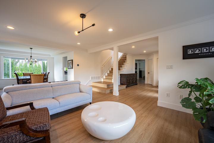 Open-plan living room with oak floors, a white sculptural coffee table and a staircase