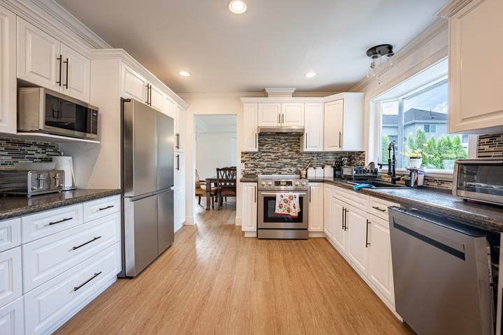 White kitchen with stainless appliances and a mosaic backsplash