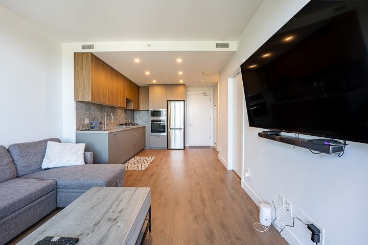 Condo living space with a wall-mounted TV and kitchen
