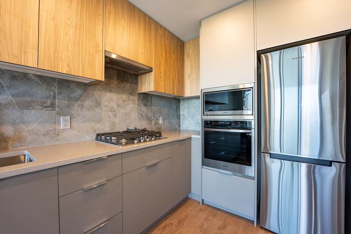 Condo kitchen with integrated oven and a tall fridge