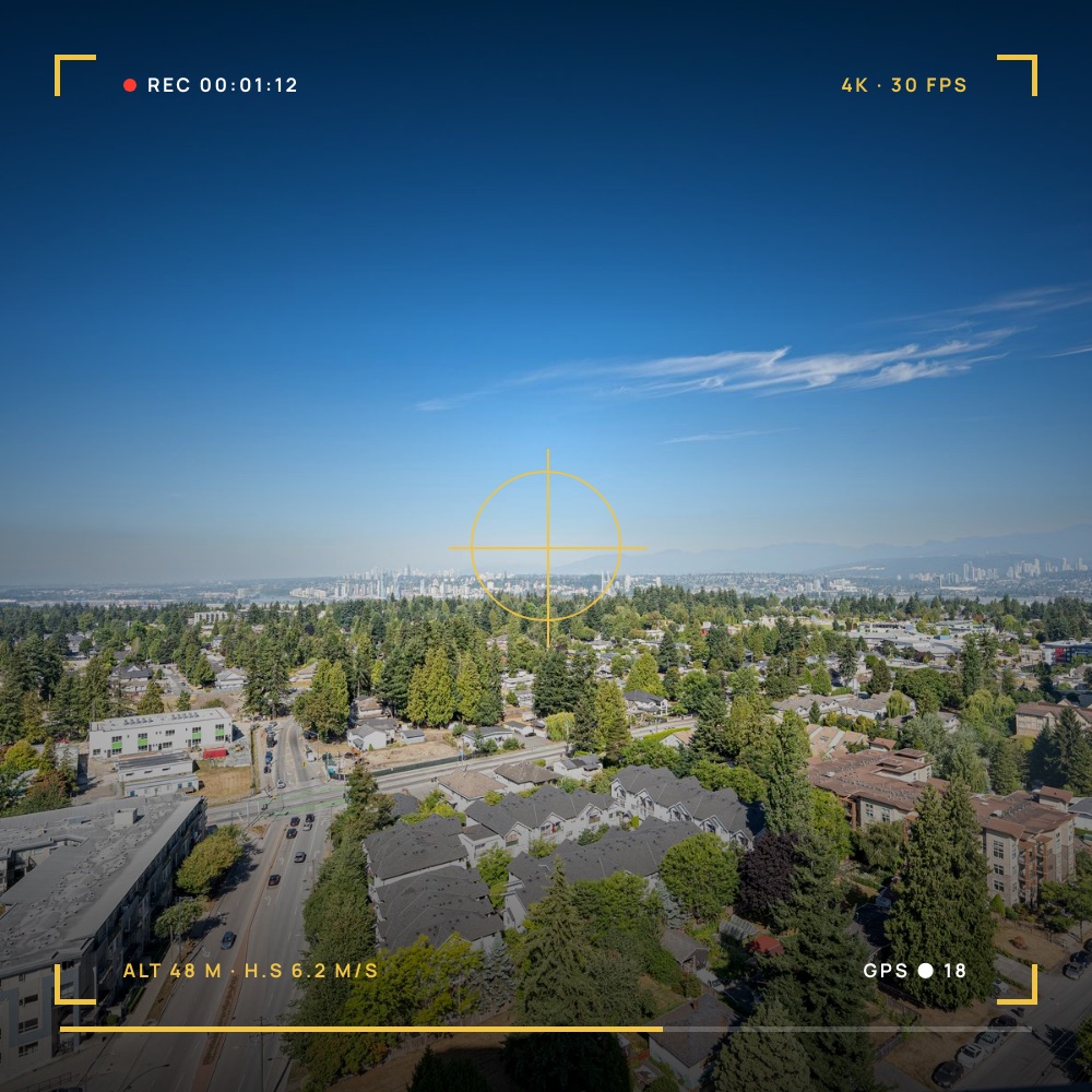 High-rise aerial view over a tree-lined neighbourhood, framed in a yellow camera viewfinder