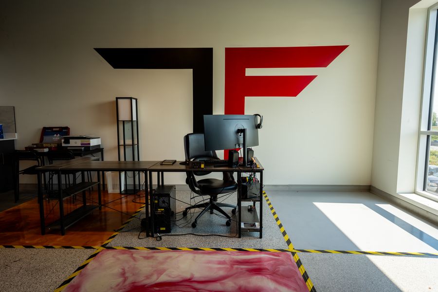 Titanium Flooring showroom — metallic, flake and marbled epoxy floor samples in front of the TF logo wall